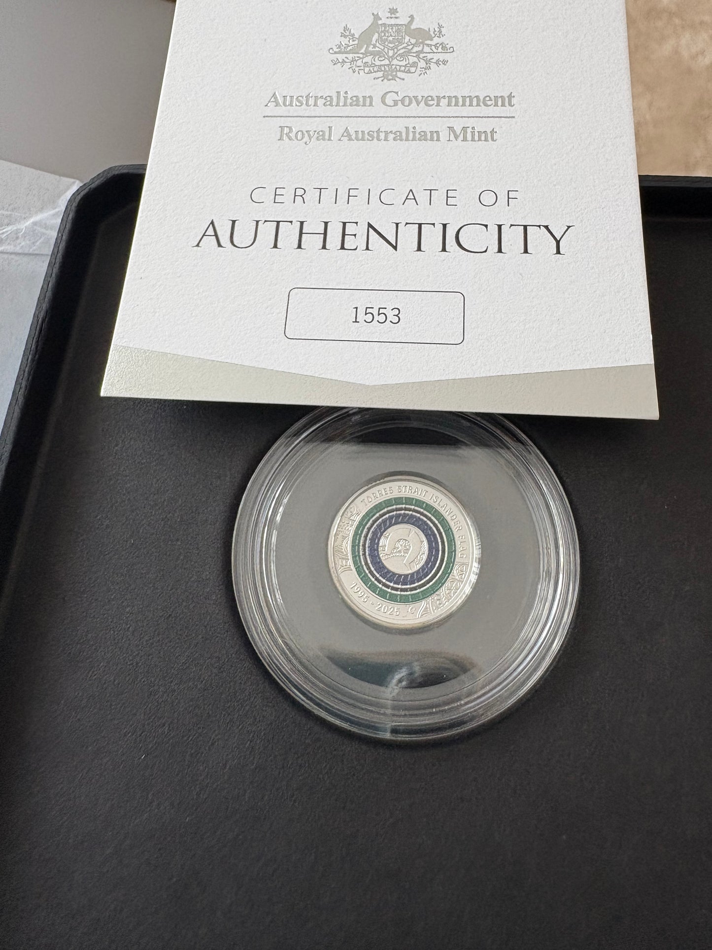 Coin in a protective case with an Australian Government Royal Australian Mint certificate of authenticity on a dark surface.
